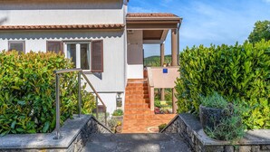 A two-story building with a covered outdoor area, a staircase leading to the upper floor, and a view of the surrounding greenery. - 2 bedroom awesome apartment in Pazin (Pazin)