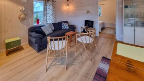 A cozy living room with a sofa, two wooden chairs, a small table, and a TV. - 1 bedroom lovely apartment in ödsmål (Ödsmål)
