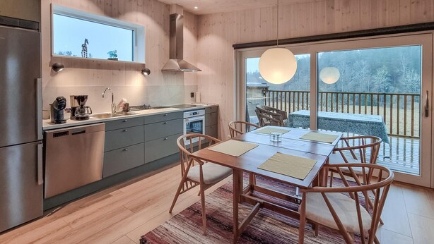A modern kitchen with a dining area, wooden flooring, and large windows overlooking a deck. - 1 bedroom lovely apartment in ödsmål (Ödsmål)