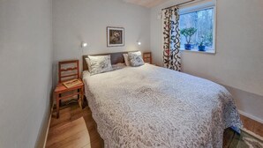 A bedroom with a large bed, two bedside tables, a chair, a framed picture on the wall, and a window with curtains. - 1 bedroom lovely apartment in ödsmål (Ödsmål)