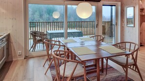 A dining area with a wooden table and chairs, a patterned rug, and a view of a deck and trees through large glass doors. - 1 bedroom lovely apartment in ödsmål (Ödsmål)