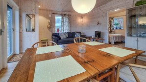 A wooden interior with a dining table, chairs, a sofa, a TV, and a kitchen area. - 1 bedroom lovely apartment in ödsmål (Ödsmål)