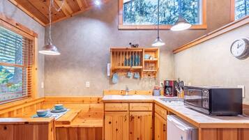 A kitchen and dining area with wooden cabinets, a microwave, and a sink.