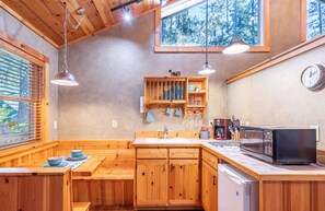 Una cocina y comedor con armarios de madera, un microondas y un lavamanos.