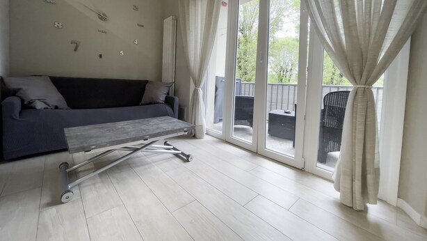 Une pièce comprenant un canapé, une petite table et donnant sur l’extérieur grâce à une porte coulissante.