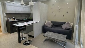 Un espace de vie compact comprenant un coin cuisine, un coin repas et un canapé.