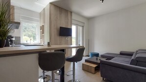 Eine moderne Küche mit einer Holzwand, einem Flachbildfernseher und einer Bar mit zwei Barhocker.