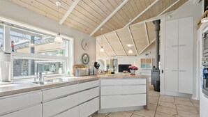 A modern kitchen with a large island, white cabinetry, and a wooden ceiling. - Stunning home in Gilleleje with sauna (Gilleleje)