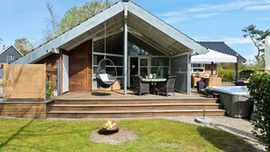 A modern house with a glass conservatory, outdoor seating, and a hot tub. - Stunning home in Gilleleje with sauna (Gilleleje)