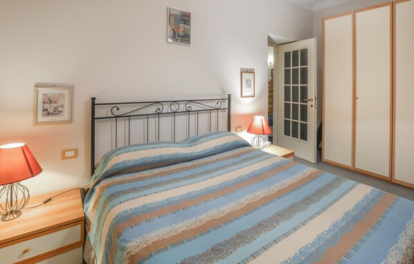 Una camera da letto con un letto, lampade sui comodini, un armadio e una porta con pannelli di vetro.
