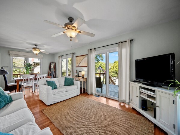 A spacious living room with a white sofa, a television, and a ceiling fan.