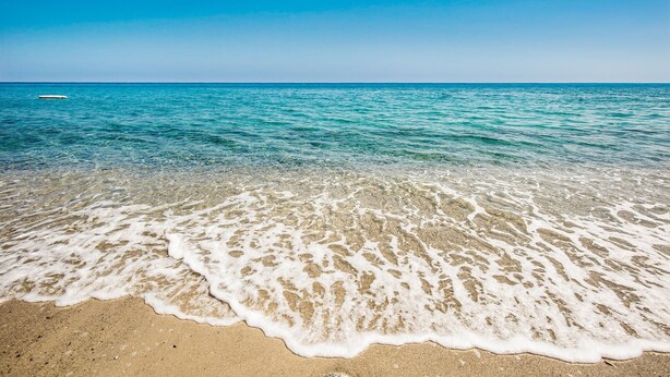 Una playa con aguas cristalinas y una orilla arenosa.