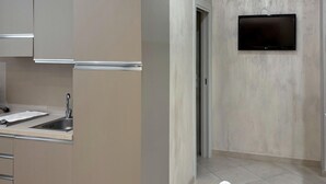 Una cocina moderna con electrodomésticos de acero inoxidable, un lavamanos integrado y un televisor de pantalla plana montado en la pared.