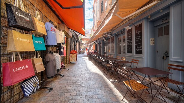 A narrow street with shops on one side and outdoor seating on the other. - 3 pièces Charmant? meynadier A2B243 (Cannes)
