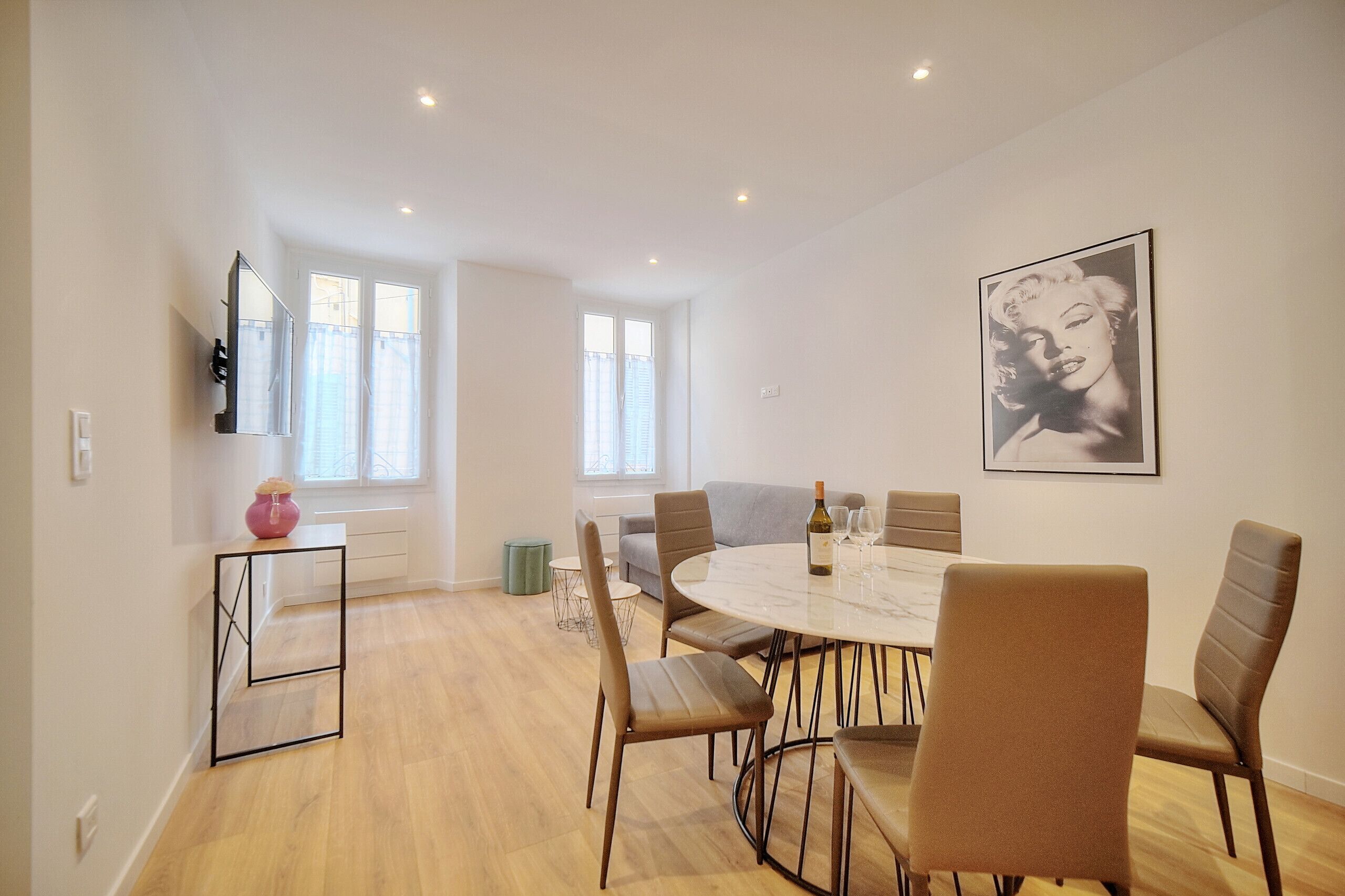 Ein moderner Essbereich mit einem runden Tisch, sechs Stühlen und einem großen Bild in einem Rahmen an der Wand.