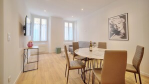 A modern dining area with a round table, six chairs, and a large framed picture on the wall. - 3 pièces Charmant? meynadier A2B243 (Cannes)