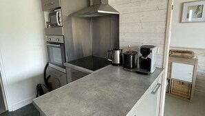 A compact kitchen with a built-in oven, microwave, and a stainless steel range hood.