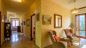 A hallway with wicker chairs, a mirror, and framed artwork on the walls.