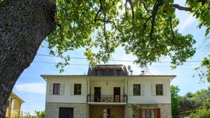 A two-story building with a balcony, stone walls, and a door with a window.