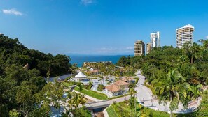 Un resort con área de piscina, palmeras y edificios altos al fondo.