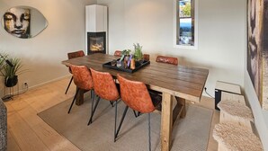 Un coin repas avec une table en bois, des chaises en cuir, une plante au centre et une cheminée.