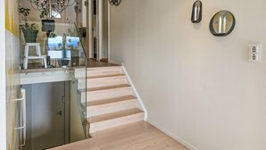 Un escalier avec des rampes en verre menant à un palier agrémenté d’une plante en pot et d’une petite table.