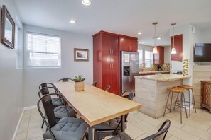 Eine moderne Küche mit Holztisch, Barhocker und Kühlschrank.