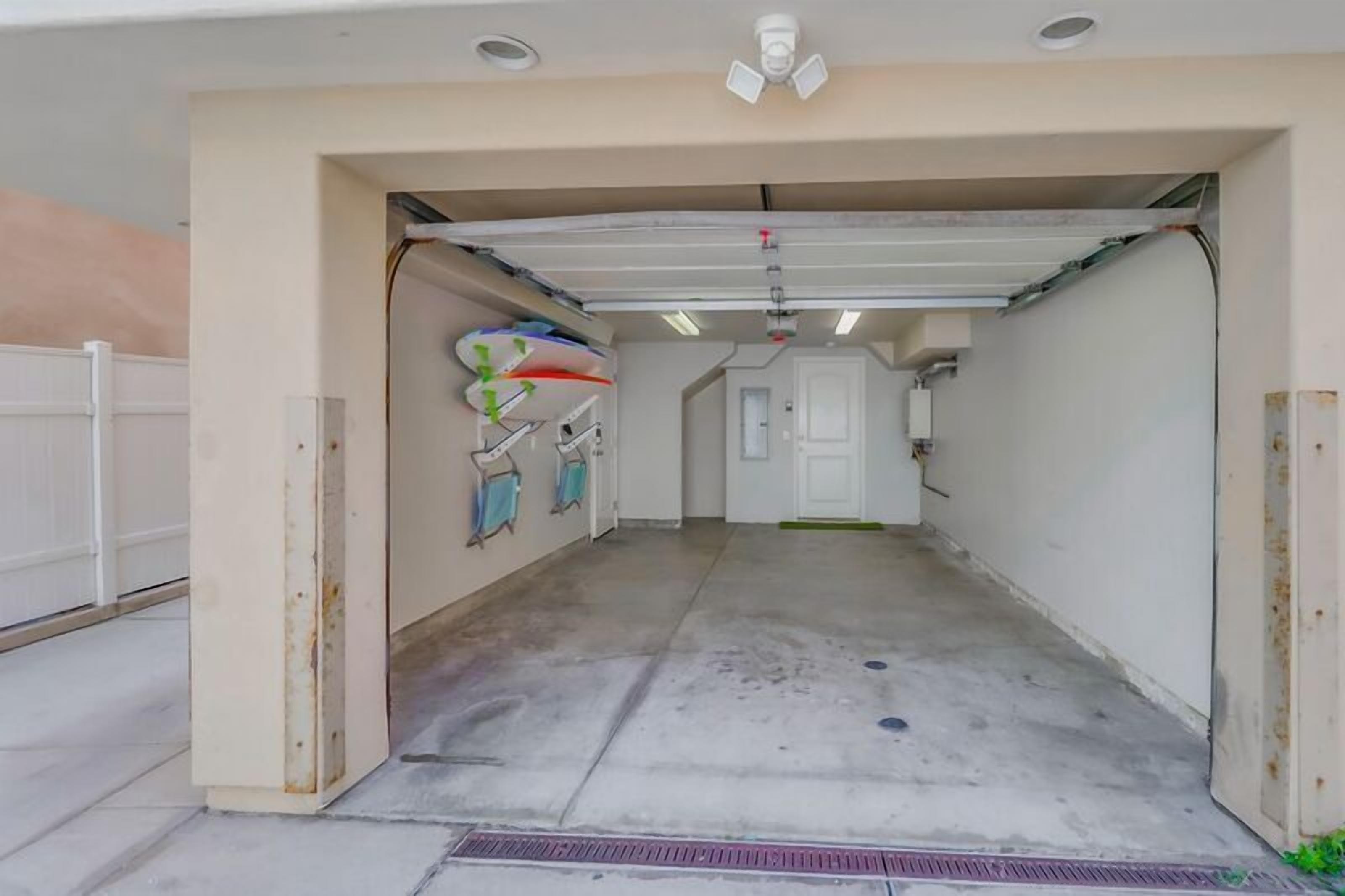 A clean, empty garage with a white door, fluorescent lighting, and a concrete floor.
