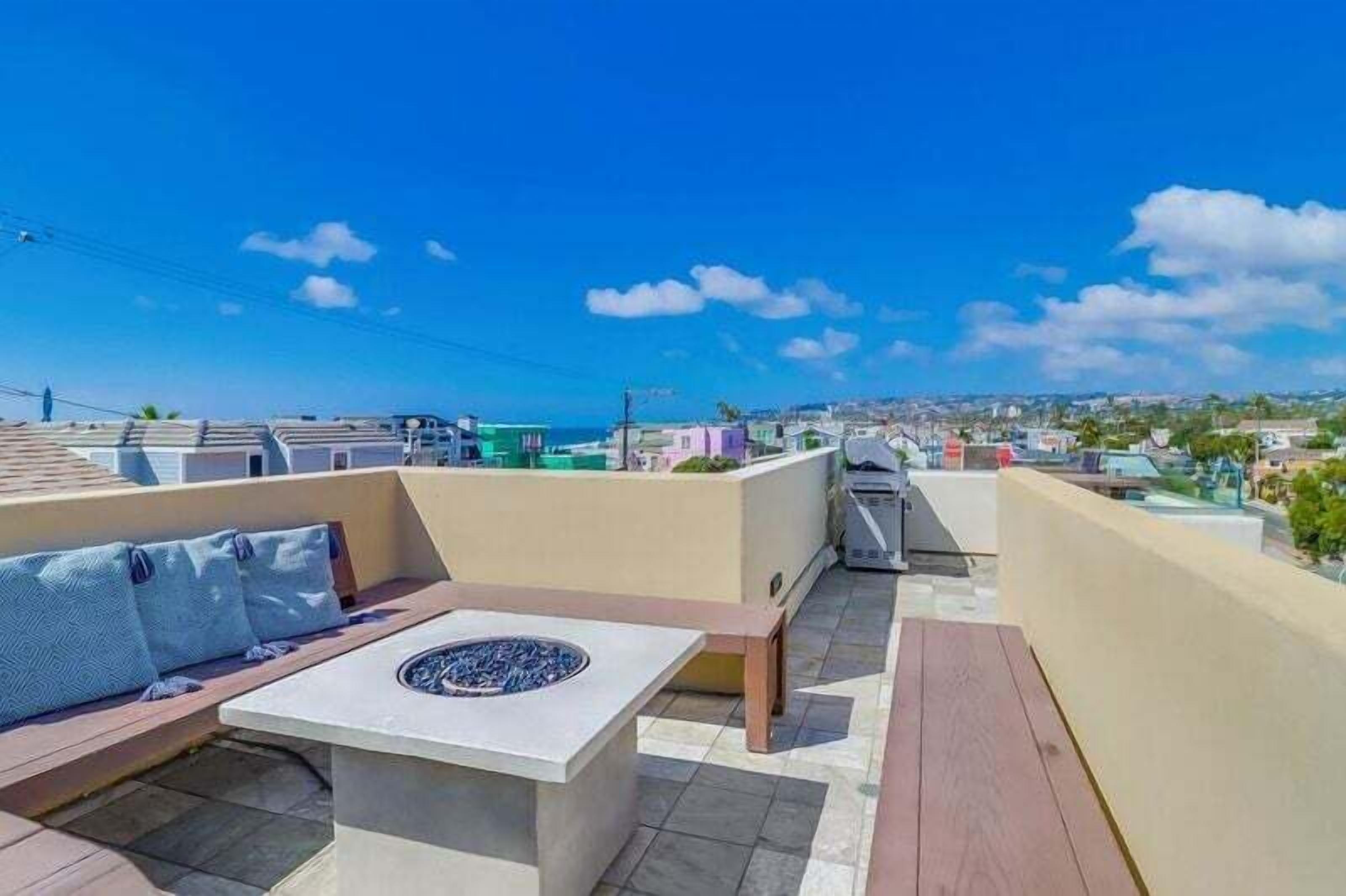 Une terrasse sur le toit dotée d’un foyer, d’un espace salon et offrant une vue sur le paysage urbain.