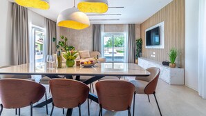 Un espace repas moderne avec une table en verre, des chaises marron et des luminaires suspendus.