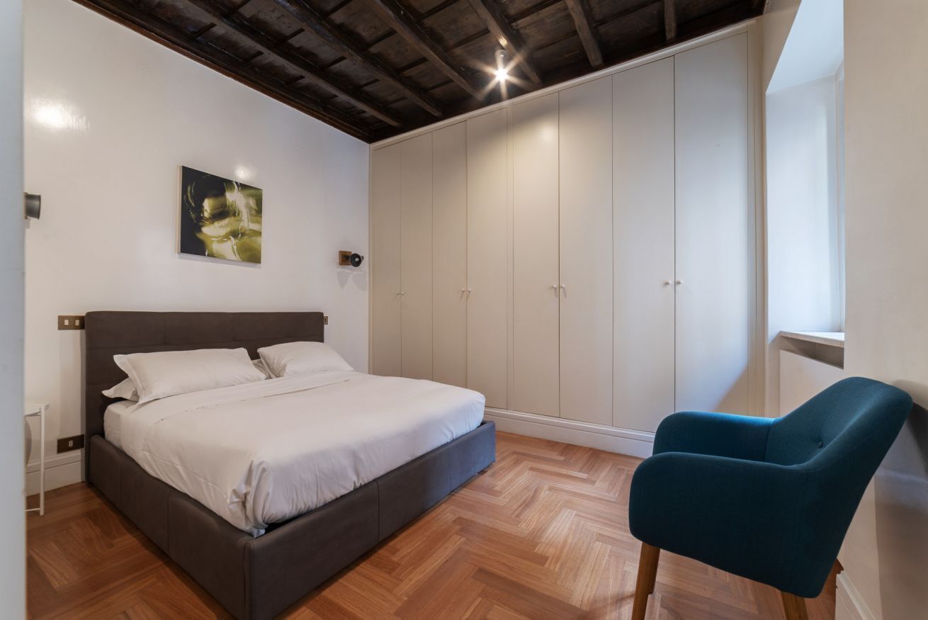 A bedroom with a bed, a wardrobe, and a chair.