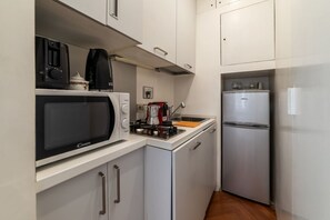 Une cuisine compacte équipée d’un four à micro-ondes, d’une machine à café et d’un réfrigérateur.