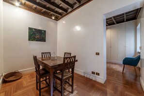 Un coin repas avec une table et des chaises en bois, un tableau accroché au mur et une chaise bleue dans un coin.