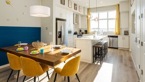 A modern kitchen with white cabinets, a central island, and a dining area with yellow chairs.