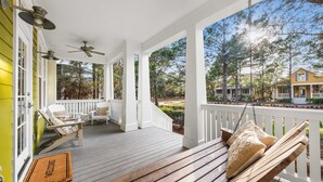 A covered porch with wooden benches and chairs, a welcome mat, and ceiling fans. - Vibrant WaterColor Haven: Electric Cart, Closet to Camp WaterColor, & Green Space Galore (Santa Rosa Beach)