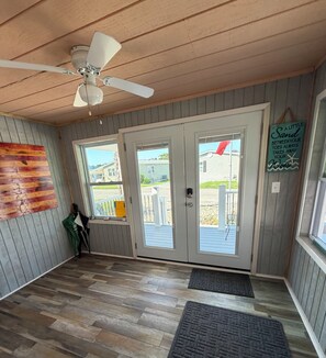 A room with a ceiling fan, a wooden floor, a sliding glass door, and a view of the outside.