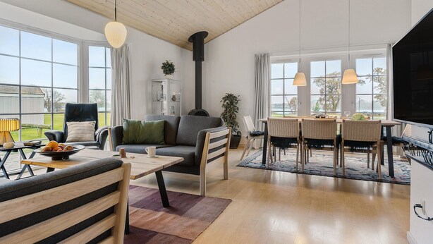 A spacious living room with a large window, a fireplace, a dining area, and a television.