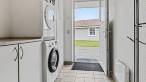 A laundry room with a washing machine and dryer, a small window, and a door leading to a covered outdoor area.
