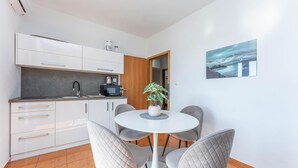 A modern kitchen with white cabinets, a black toaster, and a potted plant on the dining table. - Awesome apartment in Bibinje with WiFi (Bibinje)