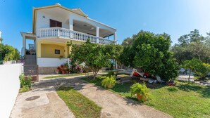 A two-story building with a balcony, surrounded by a well-maintained garden with various plants and trees. - Awesome apartment in Bibinje with WiFi (Bibinje)