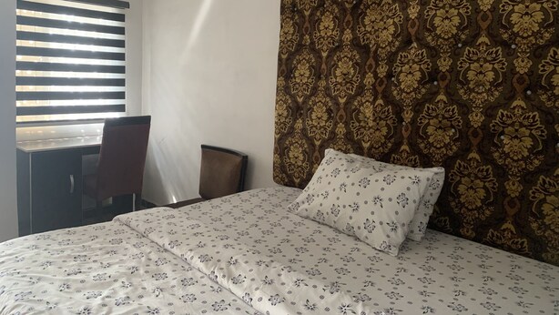 A hotel room with a bed, a desk, and a chair. - New Travellers Lodge (Lekki)