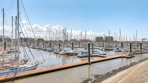 Un port de plaisance où de nombreux bateaux sont amarrés dans des eaux calmes, entouré de bâtiments et sous un ciel dégagé.
