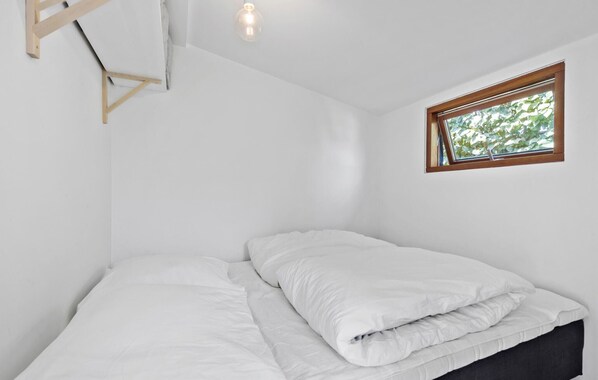 A small, white room with a bed, a window, and a light fixture. - 2 bedroom beach front home in Rønde (Rønde)
