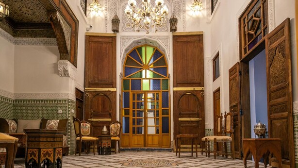 Una habitación amplia con suelo estampado, muebles de madera y un gran arco.