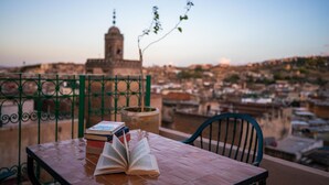 Una mesa con libros y vistas a un paisaje urbano con una torre destacada al fondo.