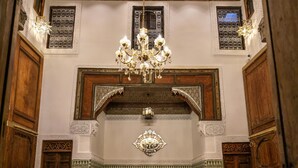 Un interior tradicional marroquí con muebles de madera ornamentados, piso estampado y una araña.