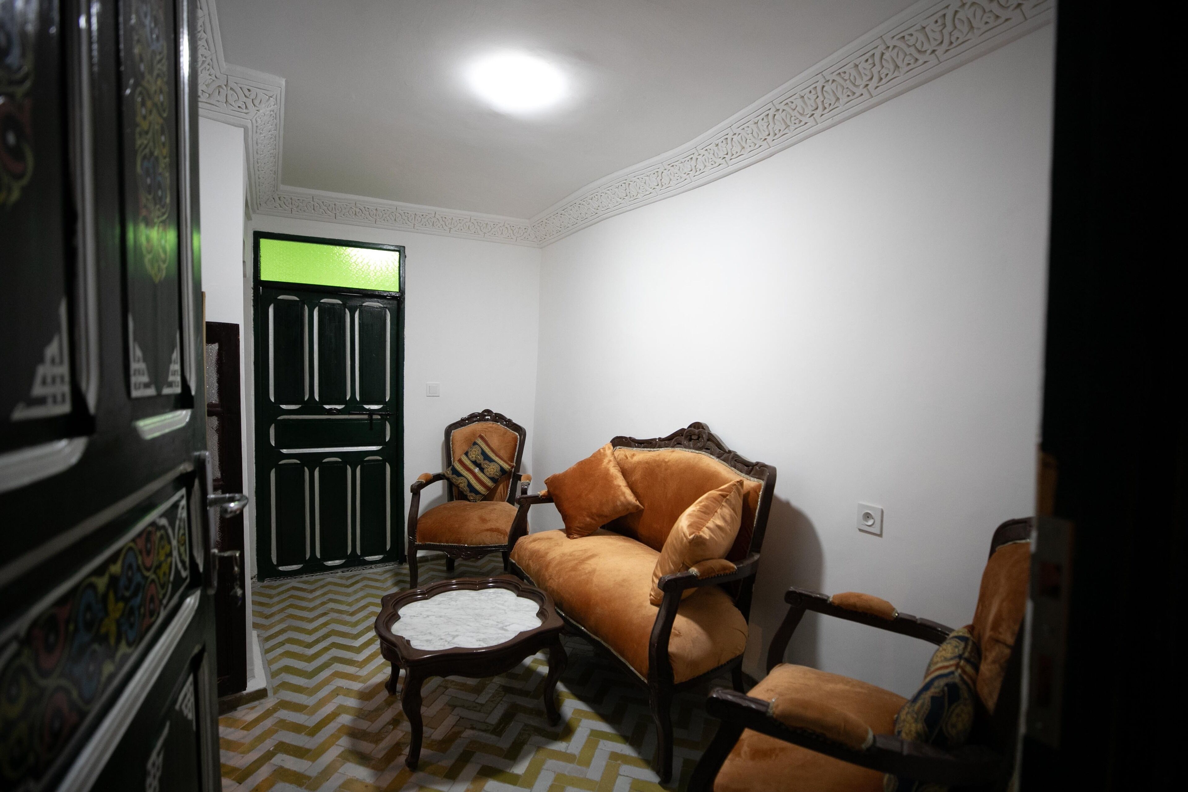 Una habitación con un sofá, dos sillones, una mesita y un espejo decorativo.