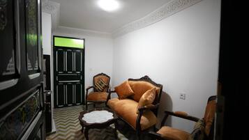Una habitación con un sofá, dos sillones, una mesita y un espejo decorativo.