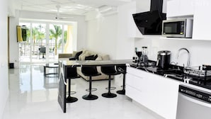Une cuisine moderne dotée d’un îlot central, de tabourets de bar noirs, d’un four à micro-ondes et d’un lave-vaisselle.