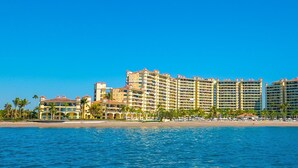 Un grand hôtel de villégiature comprenant plusieurs bâtiments, une plage et des palmiers.